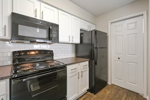 B2 kitchen with black appliances and white cabinets at Jefferson Place Apartments in Irving, TX